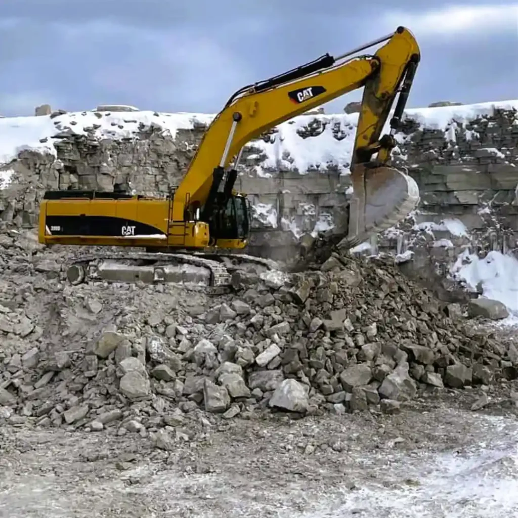 CAT excavator working granite quarry face in winter conditions Northern Ontario