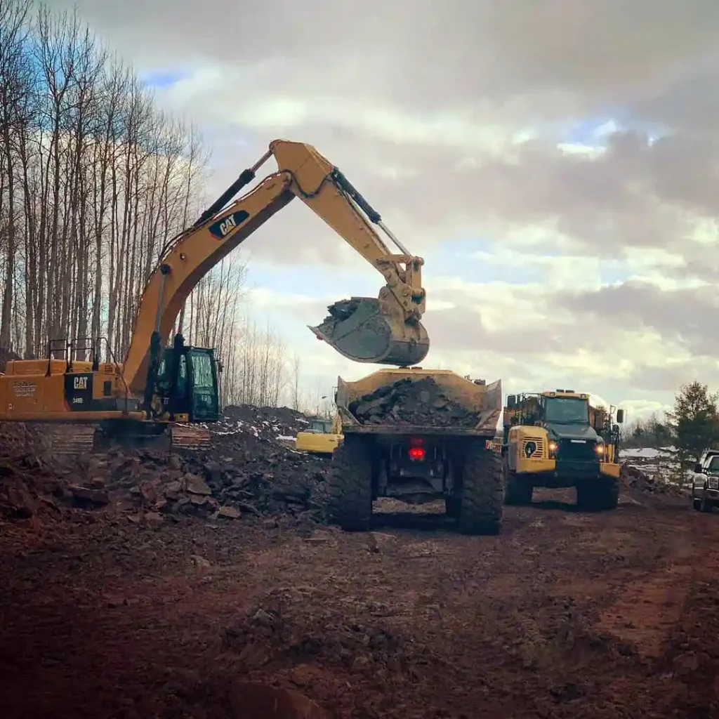 CAT excavator loading rock material into articulated haul truck at mining operation