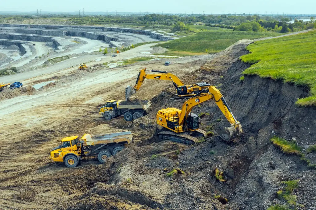 Multiple excavators and haul trucks working open pit mine with quarry benches Northern Ontario