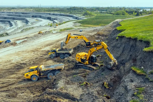 Multiple excavators and haul trucks working open pit mine with quarry benches Northern Ontario
