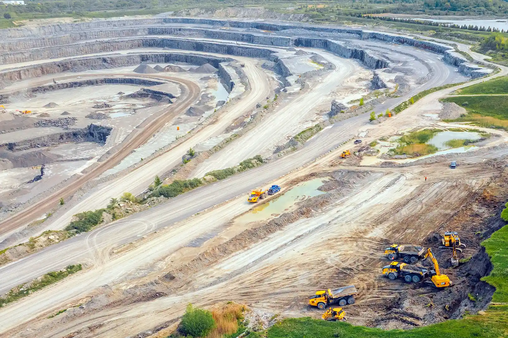 Aerial view open pit quarry showing multiple haul roads excavators and trucks extracting aggregate