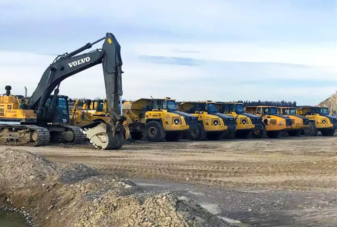 Fleet of Volvo articulated haul trucks and excavators at mining equipment yard Ontario